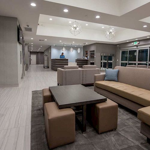 This image shows a spacious, modern lobby with ample seating, including sofas, chairs, and a central coffee table, designed for comfort and relaxation.