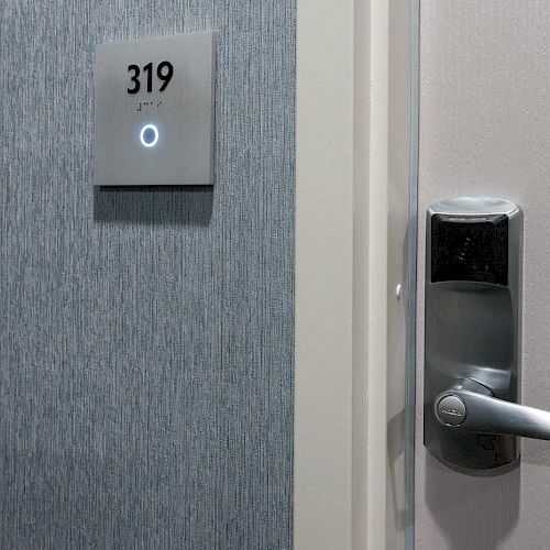 The image shows a hotel room door, numbered 319, with an electronic lock and door handle on a textured wall background.