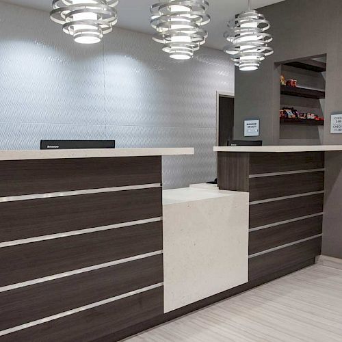 The image shows a modern reception area with dark wood paneling, pendant lights, and a clean, minimalist design.